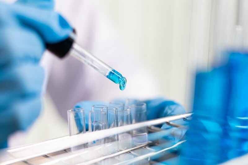 Scientists are carrying blue chemical test tubes to prepare for the determination of chemical composition and biological mass in a scientific laboratory, Scientists and research in the lab Concept.