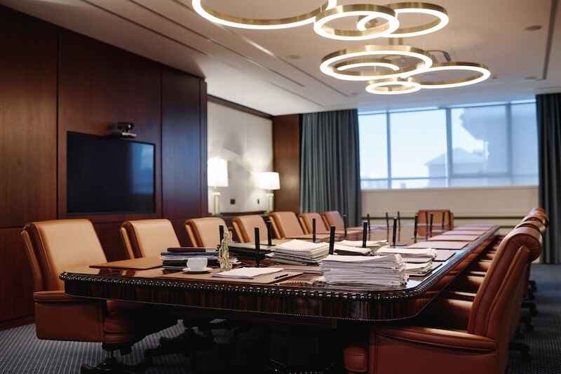 Empty boardroom in modern urban office with luxury furniture and stacks of documents on table