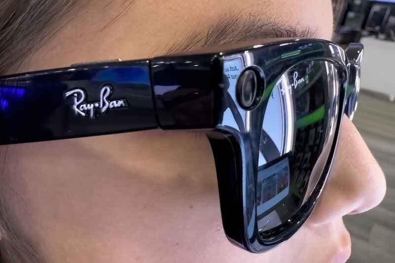 A person is wearing a pair of black Ray-Ban Meta smart glasses.